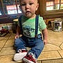 Matthew is registered to the contest to win money with this photo: baby, child, infant, shirt, jeans, suspenders, shoes, red_plaid, kitchen, counter, window, curtains, tile_floor, face, expression, sitting, indoor, person, clothing, cute