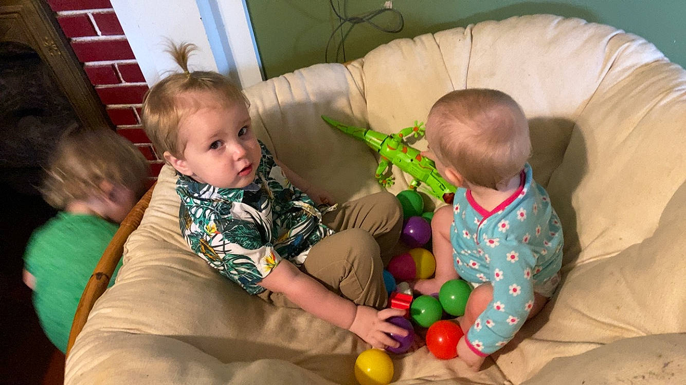 Charlie is registered to the contest to win money with this photo: baby, child, comfort, couch, face, flooring, fun, green, hair, hairstyle, human_body, interaction, iris, lap, leg, person, product, sharing, skin, toddler