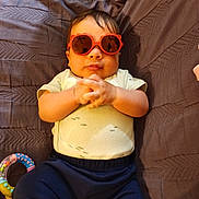 Yloan participe au concours pour gagner de l'argent avec cette photo : baby, child, sunglasses, toy, blanket, quilted, clothing, hands, indoor, cute, infant, relaxed, person, portrait, funny, accessory, colorful, soft, babywear, casual