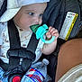 baby, child, car_seat, teething_toy, water_bottle, cap, blue_eyes, sitting, straps, clothing, infant, closeup, hand, face, safety, warning_label, seatbelt, cute, indoors, portrait