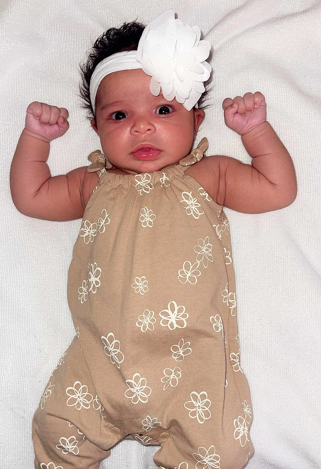 Azariah joined the competition — help win amazing prizes! baby, infant, flower_headband, onesie, beige_clothing, white_flower, raised_arms, lying_down, blanket, cute, portrait, child, skin, face, head, hand, newborn, baby_girl, expression, soft_texture