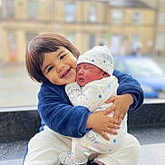 Ghaith is registered to the contest to win money with this photo: baby, blurred_background, caring, child, cute, family, happy, hat, hugging, indoor, love, newborn, pajamas, portrait, sleeping, smiling, toddler, urban, warm_clothing, window