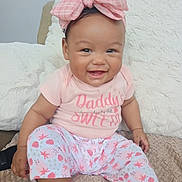 Alina is registered to the contest to win money with this photo: baby, child, smiling, pink_bow, pink_clothing, sitting, couch, blanket, happy, cute, infant, indoor, portrait, headband, patterned_pants, person, young_child, cozy, comfort, home