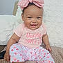 baby, child, smiling, pink_bow, pink_clothing, sitting, couch, blanket, happy, cute, infant, indoor, portrait, headband, patterned_pants, person, young_child, cozy, comfort, home