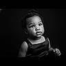 child, toddler, portrait, black_and_white, studio, face, expression, curly_hair, clothing, dress, innocence, looking_up, black_background, person, cute, young, baby, head_and_shoulders, monochrome, photography