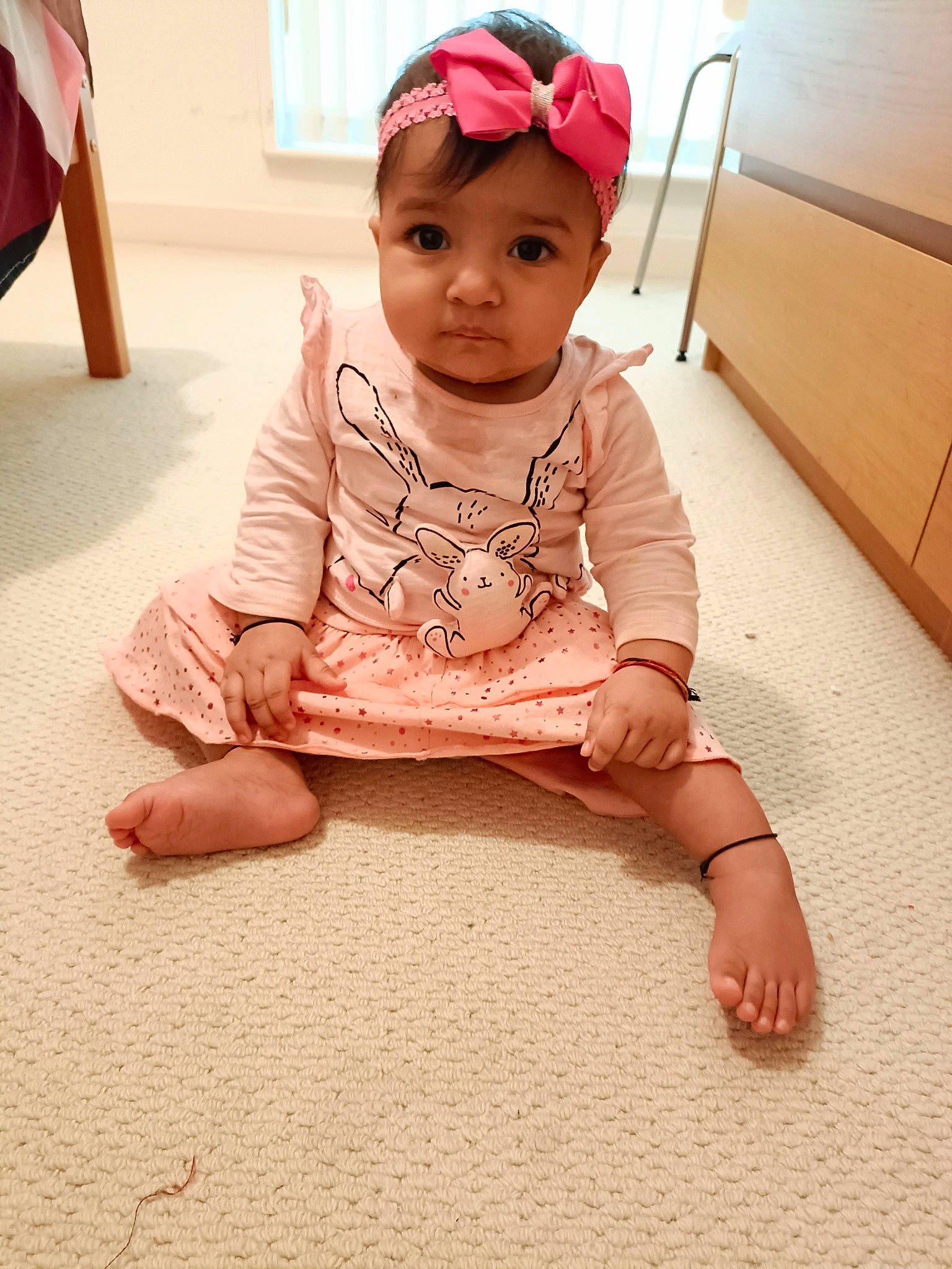 Anaya is registered to the contest to win money with this photo: baby, baby_toddler_clothing, cheek, child, dress, face, fashion_accessory, floor, flooring, fun, happy, head, headwear, lip, magenta, person, sitting, skin, sleeve, t_shirt
