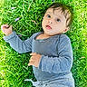 Vivaan is registered to the contest to win money with this photo: baby, casual_clothing, child, curious, daylight, expression, eyes, face, grass, gray_pants, greenery, hand, infant, lying_down, nature, outdoor, petals, portrait, striped_clothing, young_child