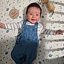 baby, infant, smiling, denim_overalls, striped_shirt, plush_toy, wooden_sign, milestone, blanket, space_theme, stars, moon, planets, cute, happy, lying_down, child, portrait, indoors, soft_toy