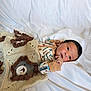 Theodore joined the competition — help win amazing prizes! baby, infant, blanket, crochet, lion, animal_pattern, bed, white_sheet, clothing, long_sleeve, person, face, hand, lying_down, cute, soft_texture, indoor, newborn, portrait, resting