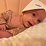 baby, infant, face, hat, lace, blanket, soft_texture, cute, portrait, lying_down, skin, hand, expression, child, newborn, cozy, indoors, headwear, smiling, closeup