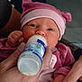 Célia participe au concours pour gagner de l'argent avec cette photo : baby, bottle, feeding, infant, hand, pink_hat, pink_clothing, closeup, care, newborn, person, skin, fingers, face, eyes, holding, milk, warmth, love, portrait
