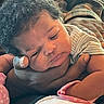 adult_hand, baby, caring, closeup, cozy, curly_hair, face, family, hand, indoors, infant, newborn, pink_mittens, plaid_shirt, portrait, resting, skin, sleepy, soft_light, striped_clothing