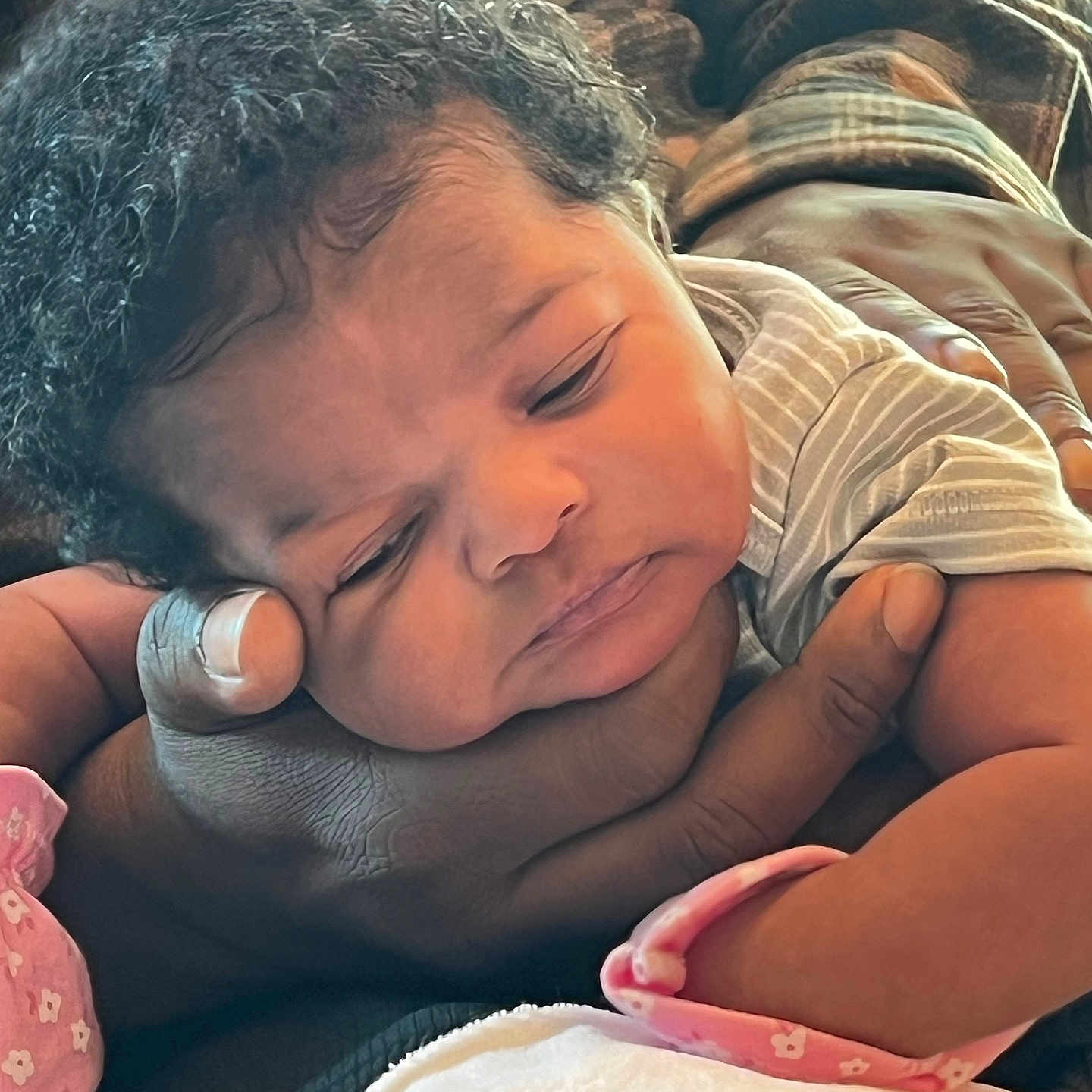 Aamyla joined the competition — help win amazing prizes! adult_hand, baby, caring, closeup, cozy, curly_hair, face, family, hand, indoors, infant, newborn, pink_mittens, plaid_shirt, portrait, resting, skin, sleepy, soft_light, striped_clothing