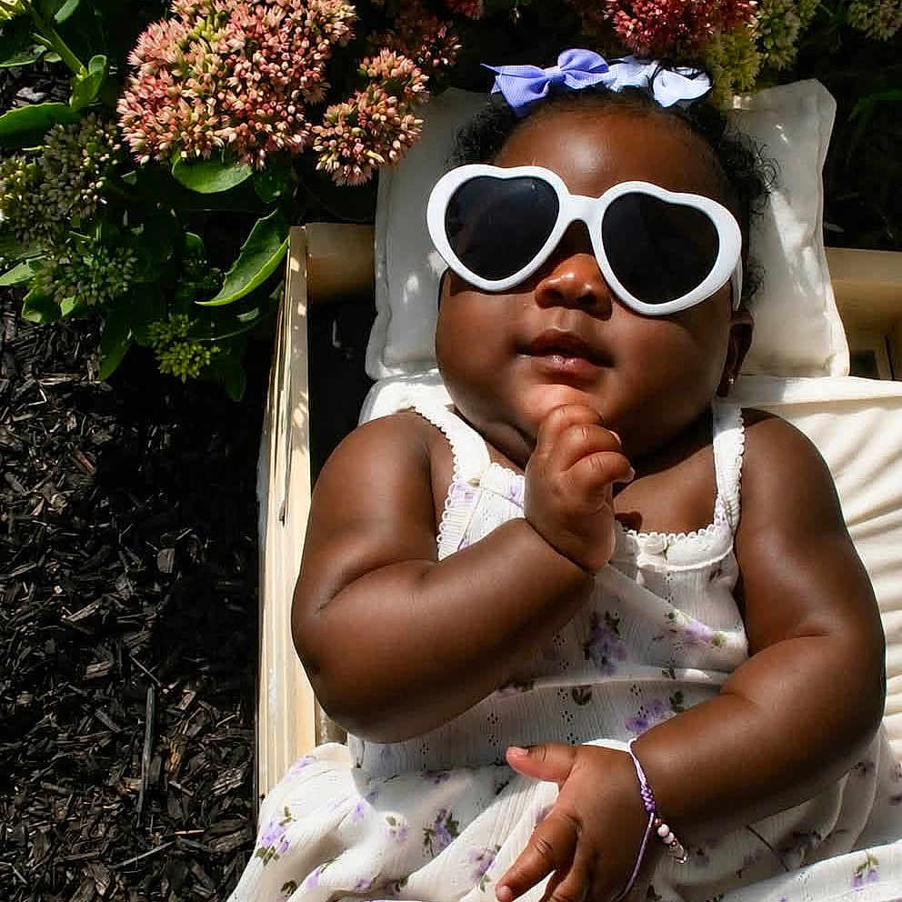 Cyanii is registered to the contest to win money with this photo: baby, child, infant, sunglasses, heart_shaped, dress, flower, flowers, wooden_blocks, months, outdoor, sunlight, skin, cute, posing, bracelet, headband, nature, milestone, smiling