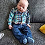 Carter-Jack is registered to the contest to win money with this photo: baby, child, plaid_shirt, blue_pants, socks, couch, gray_fabric, yellow_pillow, seated, indoor, portrait, smiling, curious, infant, casual_clothing, comfortable, cozy, home, person, young_child
