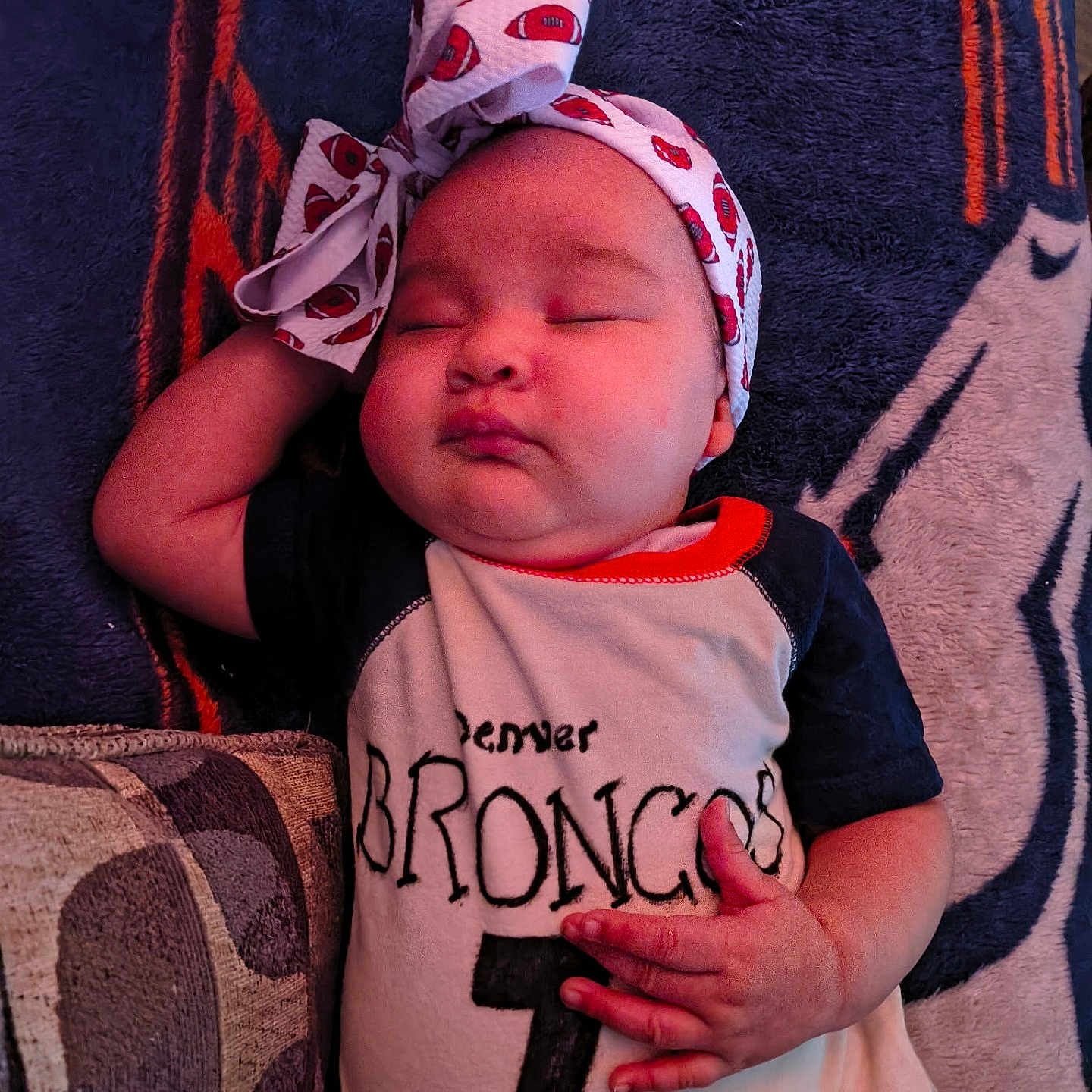 Amara joined the competition — help win amazing prizes! baby, infant, sleeping, headband, blanket, onesie, denver_broncos, hand, face, chubby_cheeks, cozy, soft_texture, resting, cute, child, portrait, indoors, comfort, relaxation, toddler