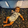 baby, infant, onesie, playpen, mattress, floral_pattern, cartoon_dog, child, lying_down, indoor, person, cute, face, foot, hand, head, sleepwear, textile, pattern, soft_furnishing