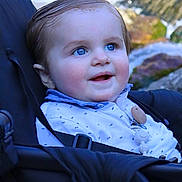 Thibault participe au concours pour gagner de l'argent avec cette photo : baby, child, blue_eyes, stroller, seat_belt, pacifier, pacifier_clip, white_shirt, smiling, cheeks, hair, closeup, portrait, outdoor, water, rocks, nature, sitting, happy, face