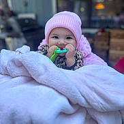 Kaileeanna joined the competition — help win amazing prizes! apparel, baby, baby_toy, blanket, child, cozy, cute, face, hands, happy, indoor, infant, leopard_print, person, pink_hat, portrait, smiling, soft, teether, warm