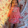 baby, infant, smiling, happy, clothing, coral_outfit, blanket, floral_pattern, lying_down, cute, child, person, indoors, socks, portrait, small_hands, cheerful, skin, head, hair_clip