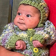 Ayla joined the competition — help win amazing prizes! baby, infant, knitted_clothing, hat, sweater, hand, adult_hand, red_shirt, face, portrait, cute, child, warm_clothing, indoor, skin, eyes, expression, holding, newborn, cozy