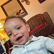 Malachi is registered to the contest to win money with this photo: child, toddler, smile, indoor, shirt, striped_shirt, face, person, wicker_chair, wall_decor, mirror, cross, lighting, home, furniture, happy, portrait, button_up, curly_hair, casual