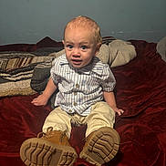 Kaynon joined the competition — help win amazing prizes! bed, beige_pants, blanket, boots, casual, child, clothing, curious, expression, footwear, furniture, home, indoor, person, portrait, sitting, striped_shirt, toddler, wall, young_child