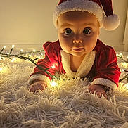 Ashly is registered to the contest to win money with this photo: baby, infant, santa_hat, christmas_lights, red_clothing, carpet, holiday, festive, cute, child, portrait, indoors, holiday_costume, glowing_lights, wide_eyes, soft_texture, christmas, celebration, festive_outfit, holiday_season