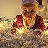baby, infant, santa_hat, christmas_lights, red_clothing, carpet, holiday, festive, cute, child, portrait, indoors, holiday_costume, glowing_lights, wide_eyes, soft_texture, christmas, celebration, festive_outfit, holiday_season