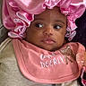 baby, infant, pink_bonnet, pink_bib, pacifier, clothing, face, looking_away, curious, child, portrait, closeup, cute, soft_texture, fabric, indoor, person, newborn, headwear, expression