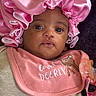 Bella joined the competition — help win amazing prizes! baby, infant, face, pink_bonnet, pink_bib, clothing, pacifier, portrait, cute, child, closeup, expression, indoor, adorable, young, person, headwear, text_embroidery, fabric, sleepwear