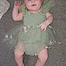 Alice is registered to the contest to win money with this photo: baby, infant, child, dress, green_dress, bow, headband, sitting, lying_down, couch, sofa, indoor, portrait, face, eyes, smiling, fashion, floral, fabric, photography