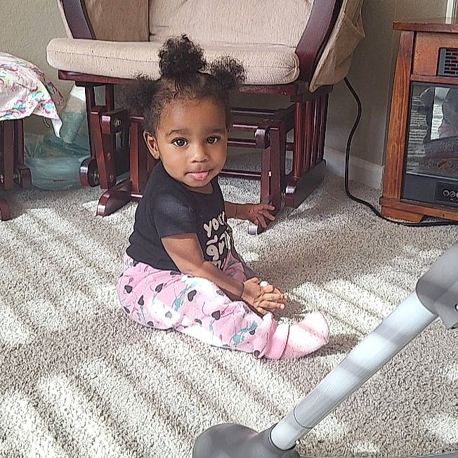 Araya is registered to the contest to win money with this photo: baby, baby_toddler_clothing, black, chair, child, comfort, drawer, floor, flooring, fun, furniture, hardwood, human_body, lap, person, product, sleeve, standing, t_shirt, toddler