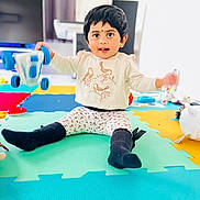 Kiyara participe au concours pour gagner de l'argent avec cette photo : toddler, child, toy, playmat, indoor, smiling, sitting, colorful, car_toy, leggings, socks, long_sleeve_shirt, black_hair, face, young_child, floor, playtime, cute, happy, home