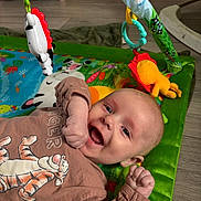 Cody is registered to the contest to win money with this photo: baby, smiling, play_mat, toy, colorful, infant, happy, floor, child, clothing, tiger_print, cute, indoor, young_child, hands_up, face, expression, playtime, bright, casual