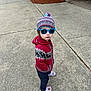 child, kid, standing, outdoor, concrete, sidewalk, knit_hat, sunglasses, red_sweater, patterned_sweater, pants, purple_crocs, footwear, casual_clothing, cool_pose, confident, young, person, daylight, residential_area