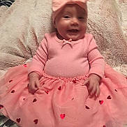 Sophia is registered to the contest to win money with this photo: baby, pink_outfit, bow_headband, smiling, sitting, blanket, heart_patterns, cute, infant, happy, soft_texture, indoors, child, portrait, tutu_skirt, adorable, young_child, headwear, hands, cozy