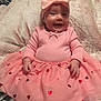 baby, pink_outfit, bow_headband, smiling, sitting, blanket, heart_patterns, cute, infant, happy, soft_texture, indoors, child, portrait, tutu_skirt, adorable, young_child, headwear, hands, cozy