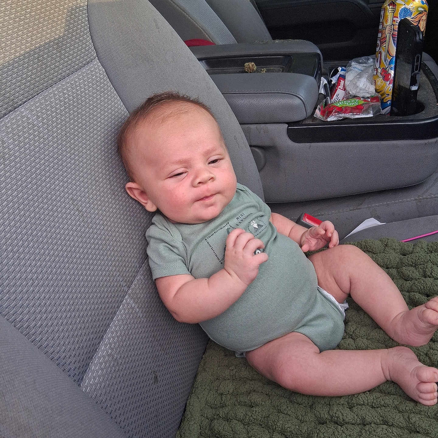 Cooper joined the competition — help win amazing prizes! baby, infant, child, car, car_seat, vehicle_interior, onesie, blanket, sitting, lying_down, face, portrait, eyes, smiling, relaxed, snacks, cup_holder, fabric, indoor, road_trip