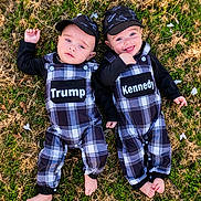 Trump And Kennedy is registered to the contest to win money with this photo: baby, black_cap, child, clothing, cute, foot, grass, happy, headwear, infant, lying_down, names, nature, outdoor, person, plaid_overalls, playful, smiling, twin, two_people