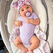 Kaitlyn joined the competition — help win amazing prizes! baby, infant, child, portrait, lying_down, pacifier, hat, bow, floral, lavender, purple, onesie, blanket, cushion, baby_seat, indoor, cozy, smiling, face, feet