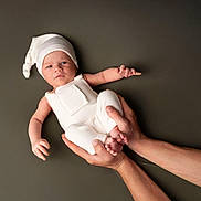 Elyo a rejoint le concours — aidez-le/la à gagner de superbes lots ! baby, infant, hands, white_clothing, hat, portrait, studio, cute, newborn, child, person, skin, expression, holding, background, minimalist, soft_lighting, peaceful, human, resting