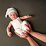 baby, infant, hands, white_clothing, hat, portrait, studio, cute, newborn, child, person, skin, expression, holding, background, minimalist, soft_lighting, peaceful, human, resting