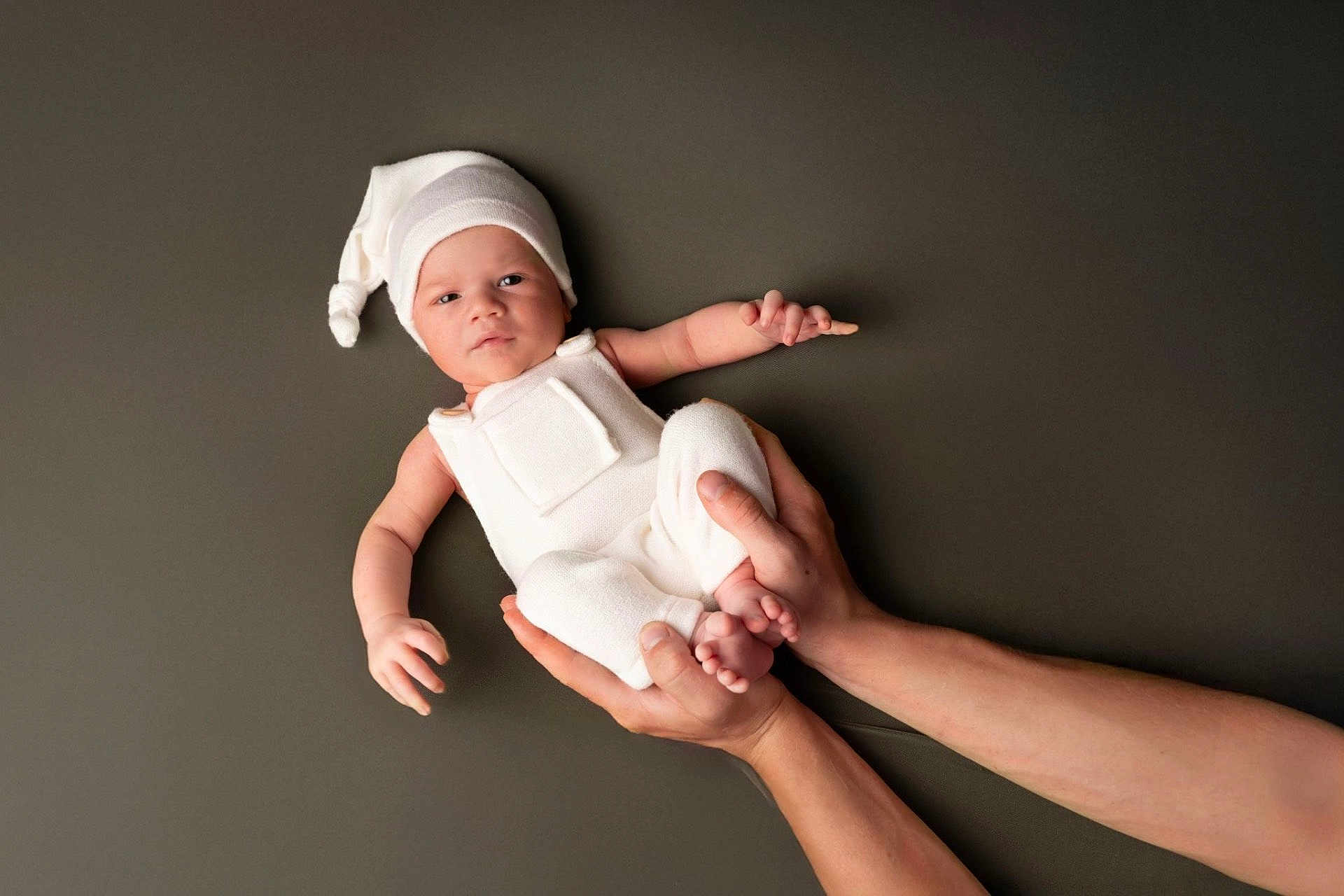 Elyo a rejoint le concours — aidez-le/la à gagner de superbes lots ! baby, infant, hands, white_clothing, hat, portrait, studio, cute, newborn, child, person, skin, expression, holding, background, minimalist, soft_lighting, peaceful, human, resting