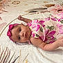 baby, infant, child, girl, lying_down, blanket, headband, pink_clothing, floral_pattern, cute, portrait, indoors, skin, face, eyes, arm, hand, soft_texture, resting, young