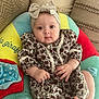baby, infant, headband, bow, dress, floral_pattern, cushion, colorful, hand, foot, face, eyes, indoors, comfort, cute, child, patterned_clothing, soft_toy, pillow, relaxation