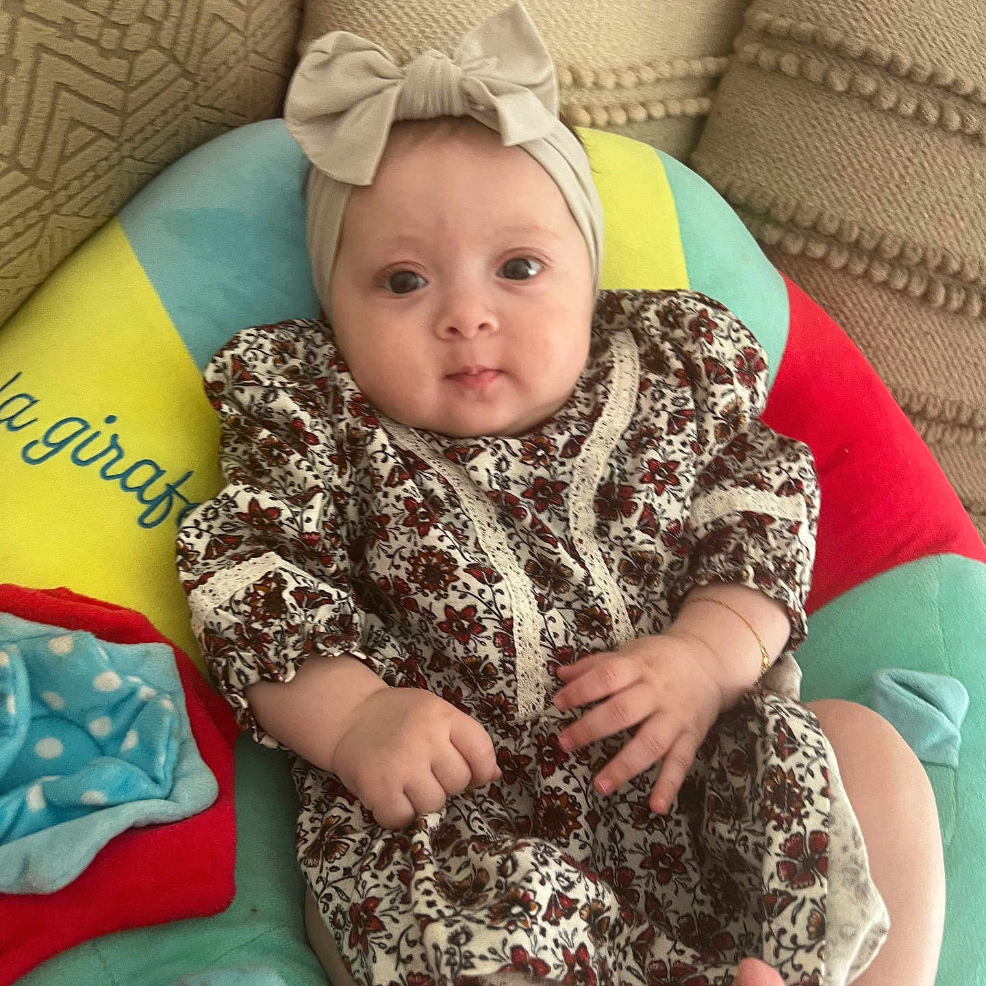 Rania a rejoint le concours — aidez-le/la à gagner de superbes lots ! baby, bow, child, colorful, comfort, cushion, cute, dress, eyes, face, floral_pattern, foot, hand, headband, indoors, infant, patterned_clothing, pillow, relaxation, soft_toy