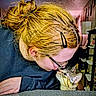 person, cat, indoor, glasses, hair_clip, tabby_cat, table, face, close_up, interaction, pet, home, furniture, sweatshirt, curiosity, cozy, warm_lighting, nose_to_nose, affection, animal