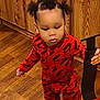 A'Mir is registered to the contest to win money with this photo: toddler, child, red_clothing, puma, onesie, vacuum_cleaner, wood_floor, indoor, person, furniture, hair, standing, curious, baby, flooring, home, young_child, small_person, holding, appliance