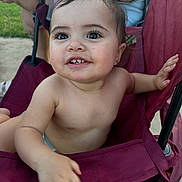 Izabella is registered to the contest to win money with this photo: baby, bare_chest, chair, child, curious, earring, eyes, fabric, face, grass, hair, hand, happy, outdoor, person, seat, skin, smiling, toddler, tooth